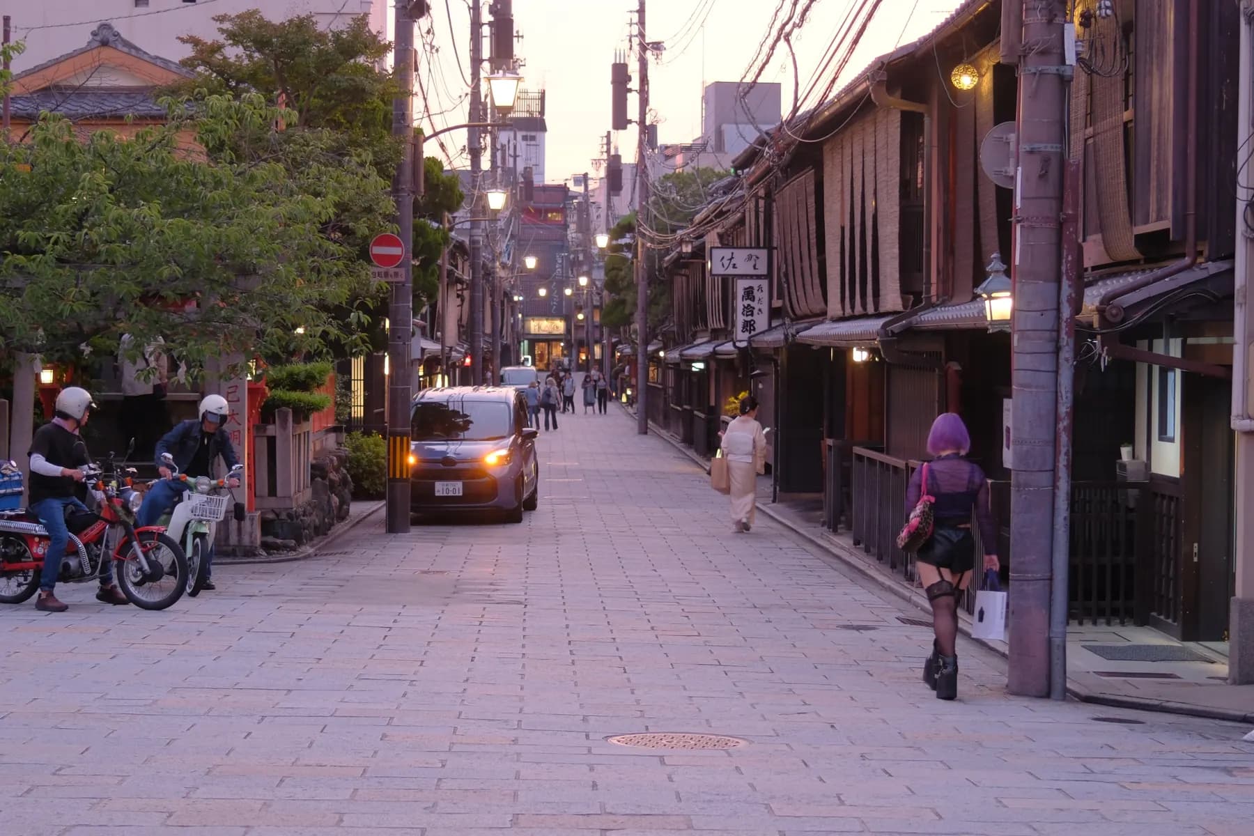 A serene sunset scene in a traditional Japanese street with people and vehicles