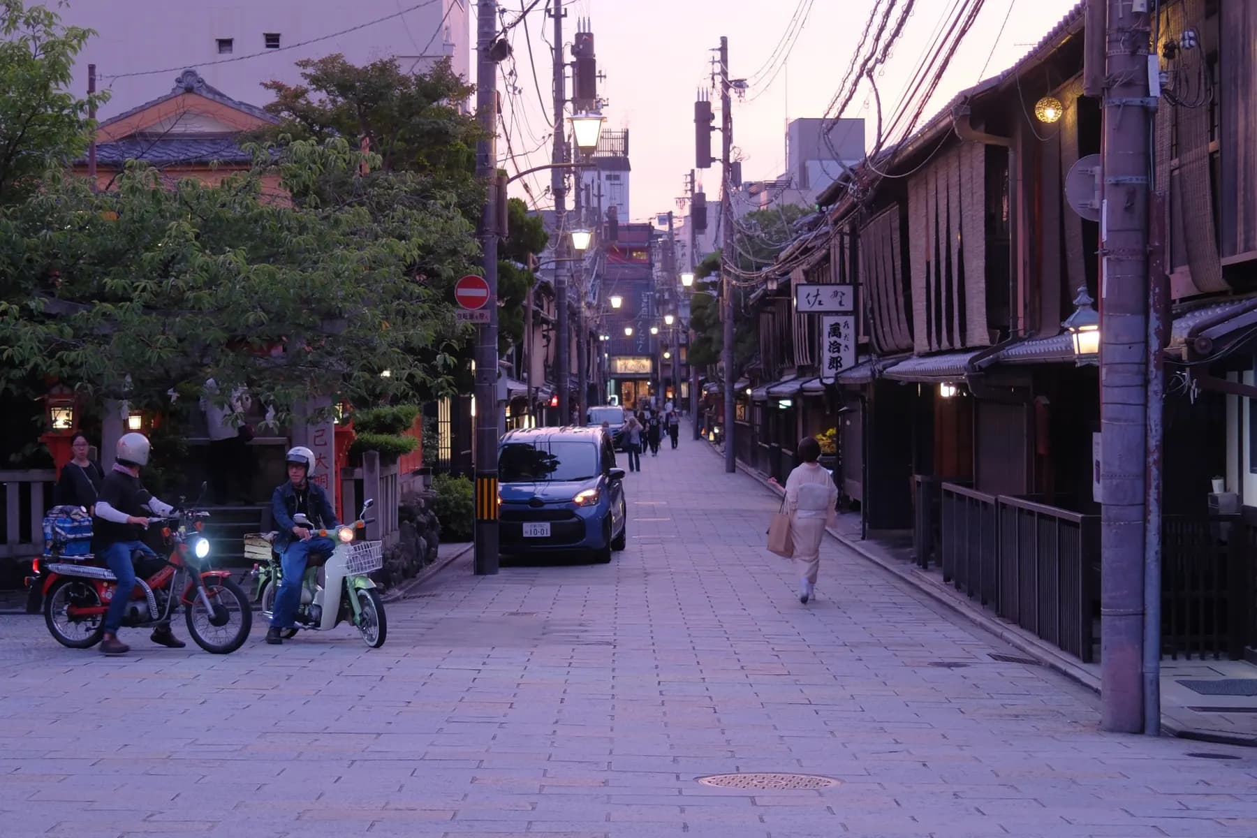 A serene street scene at sunset with people and vehicles
