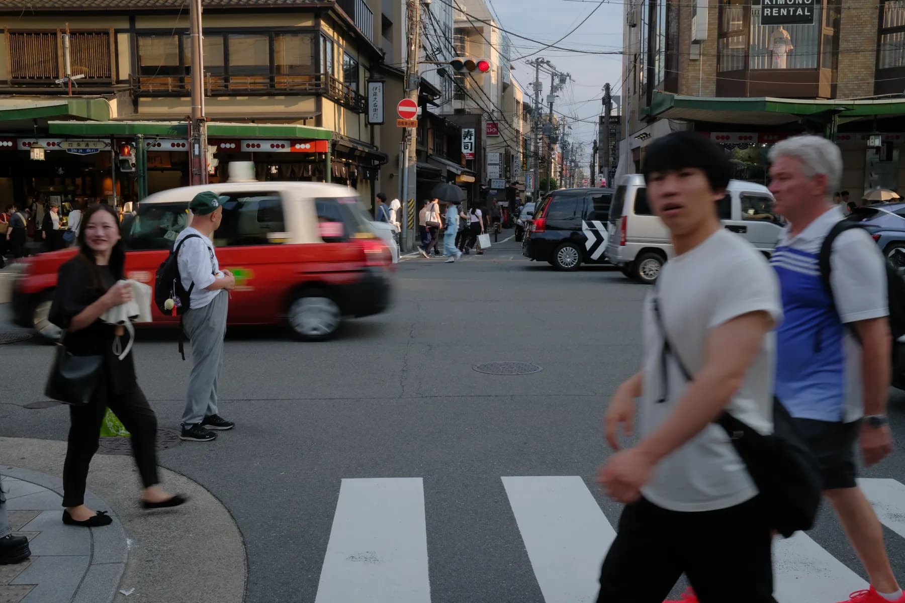 A bustling urban street scene with pedestrians, cars, and buildings, captured in a candid moment