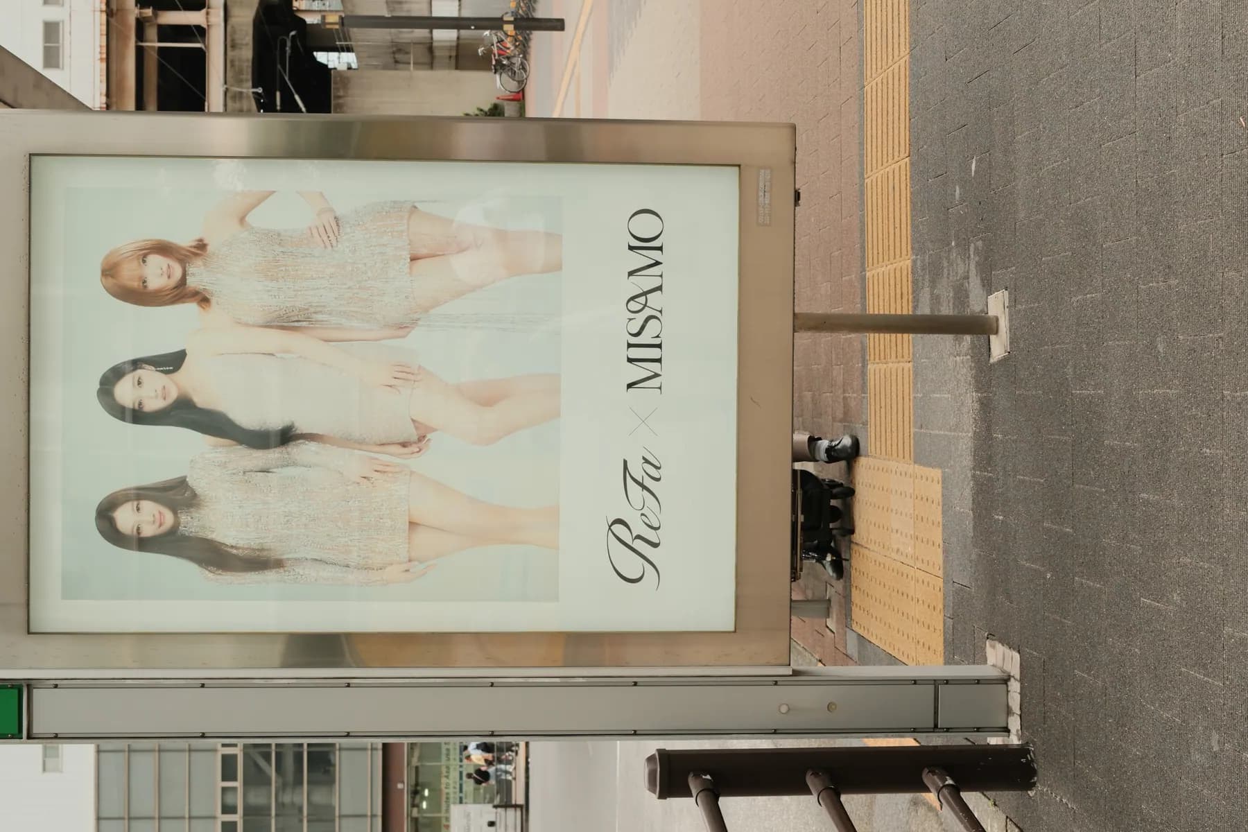A poster featuring three women in elegant silver dresses, promoting a collaboration between ReFa and MISAMO