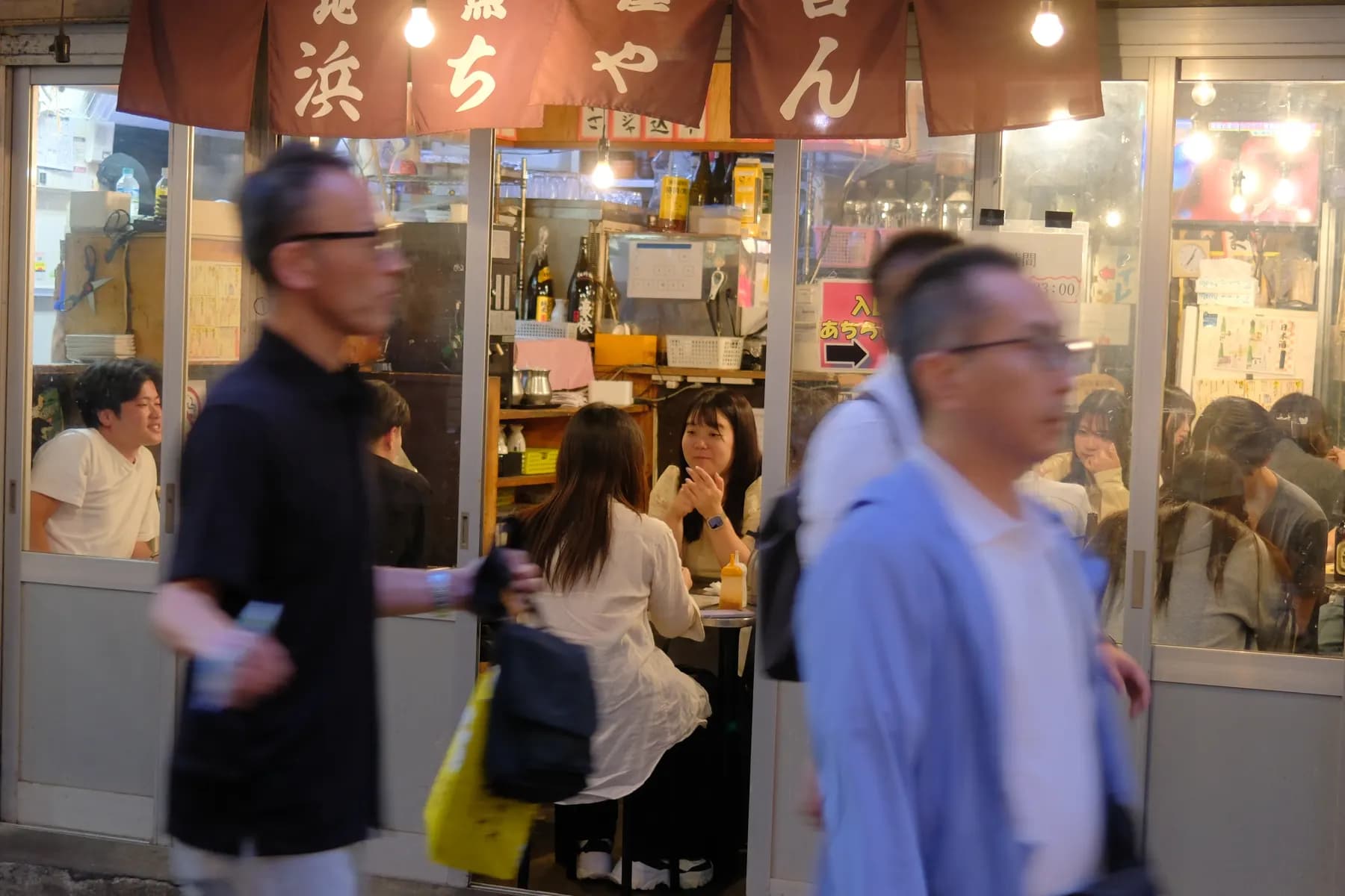 A bustling street scene at a restaurant with people dining and walking by