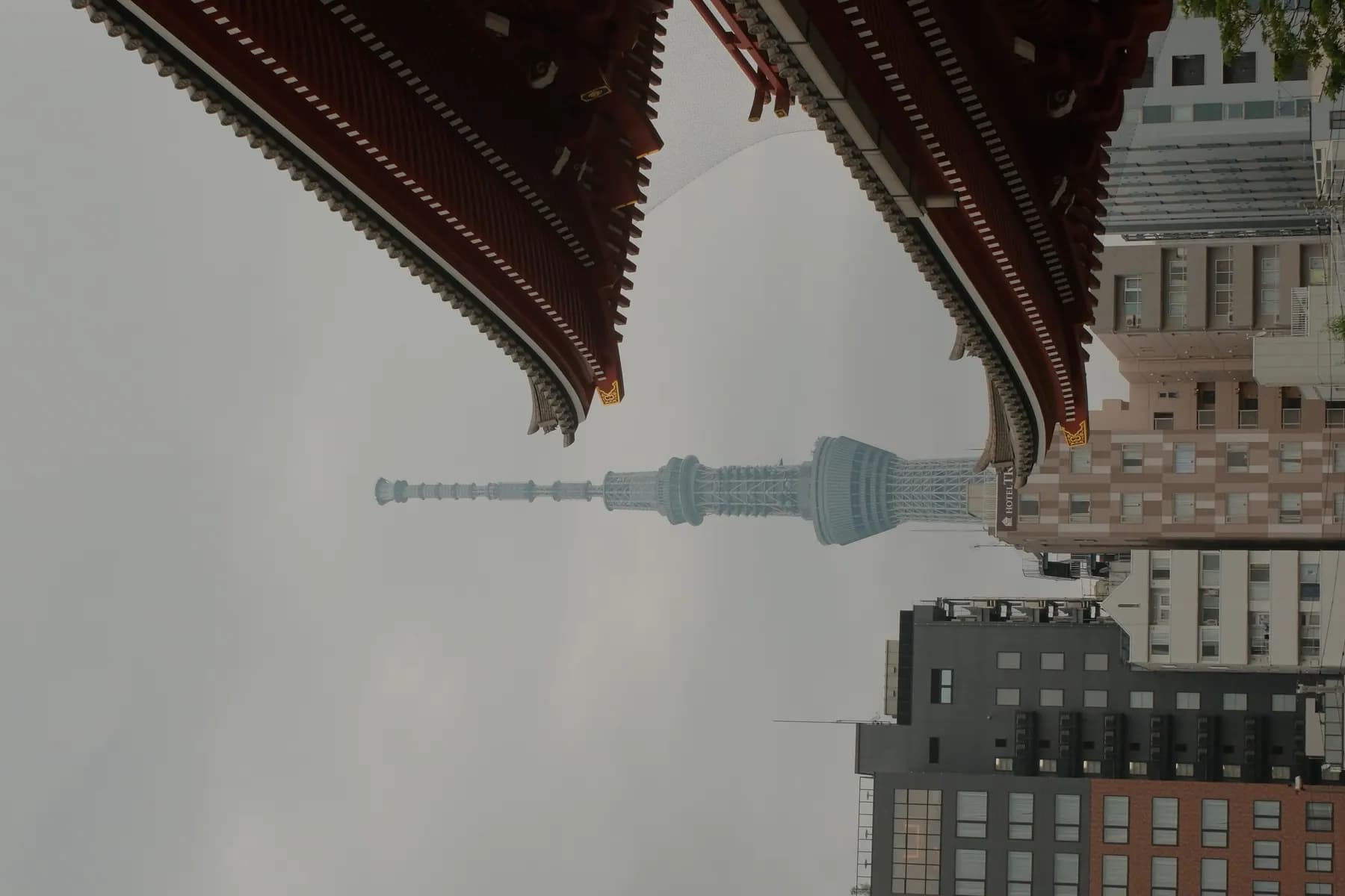 A modern Tokyo Skytree contrasts with traditional architecture under a cloudy sky