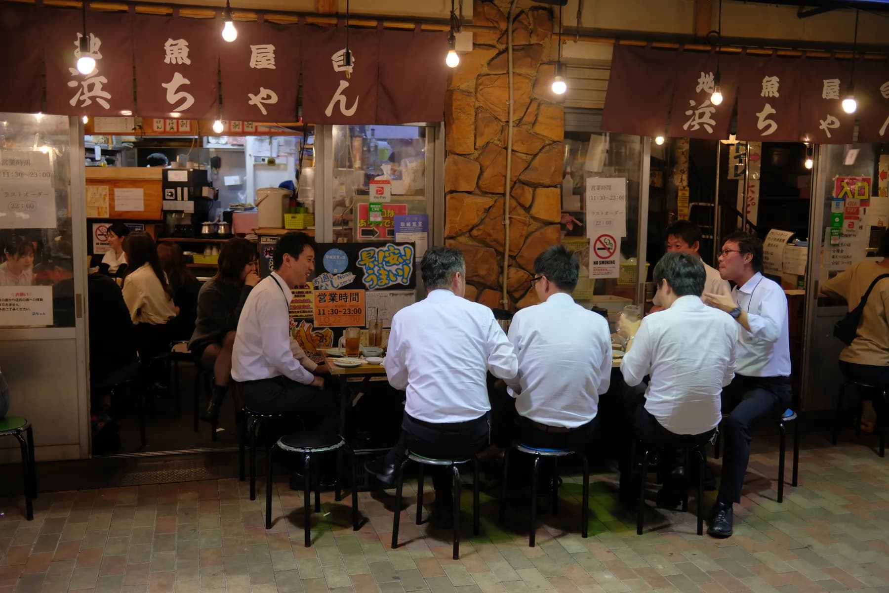 A group of people enjoying a meal at a street-side restaurant at night