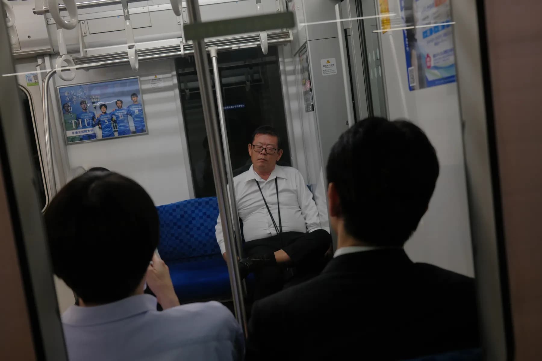 A candid moment of commuters on a train, with one person sitting and looking out the window