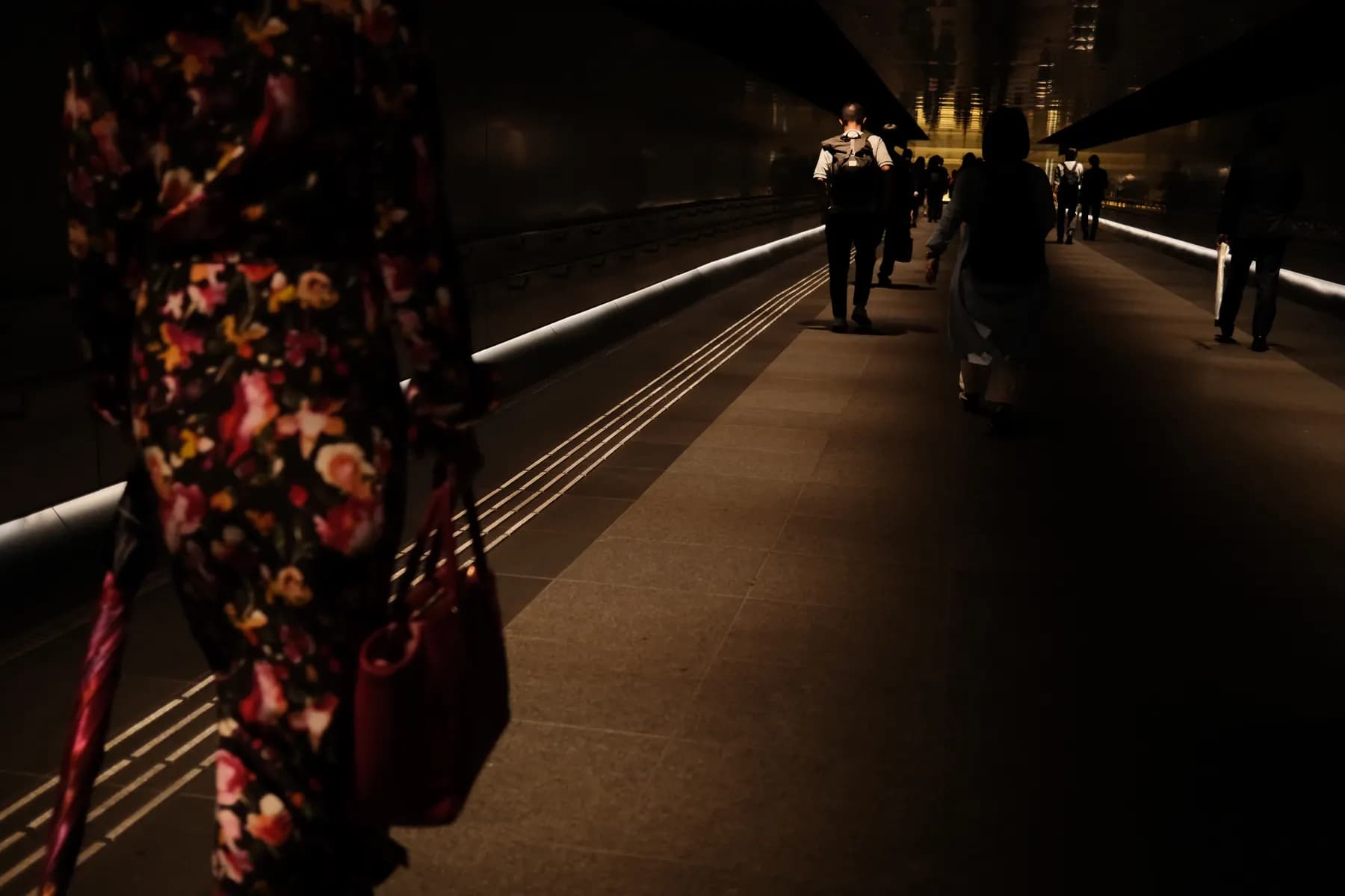 A dimly lit urban scene with people walking in a tunnel, creating a mysterious and somewhat eerie atmosphere