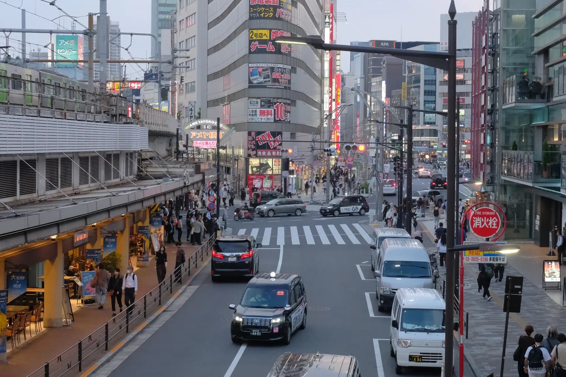 A bustling urban street scene with pedestrians, vehicles, and commercial signage